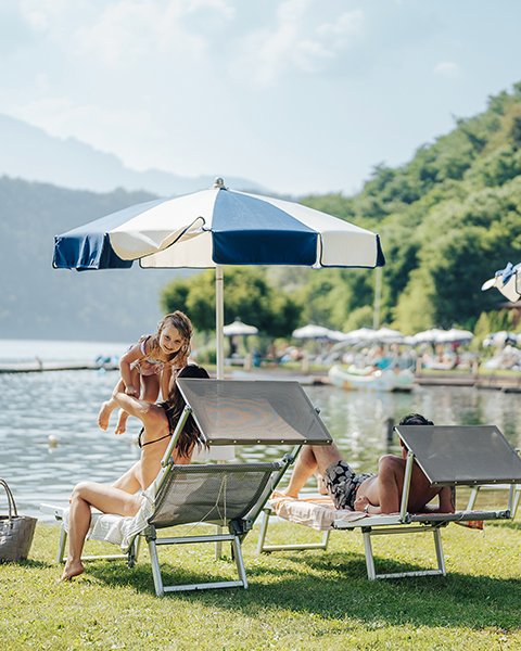 Famiglia che si rilassa sulle sdraio in riva al lago